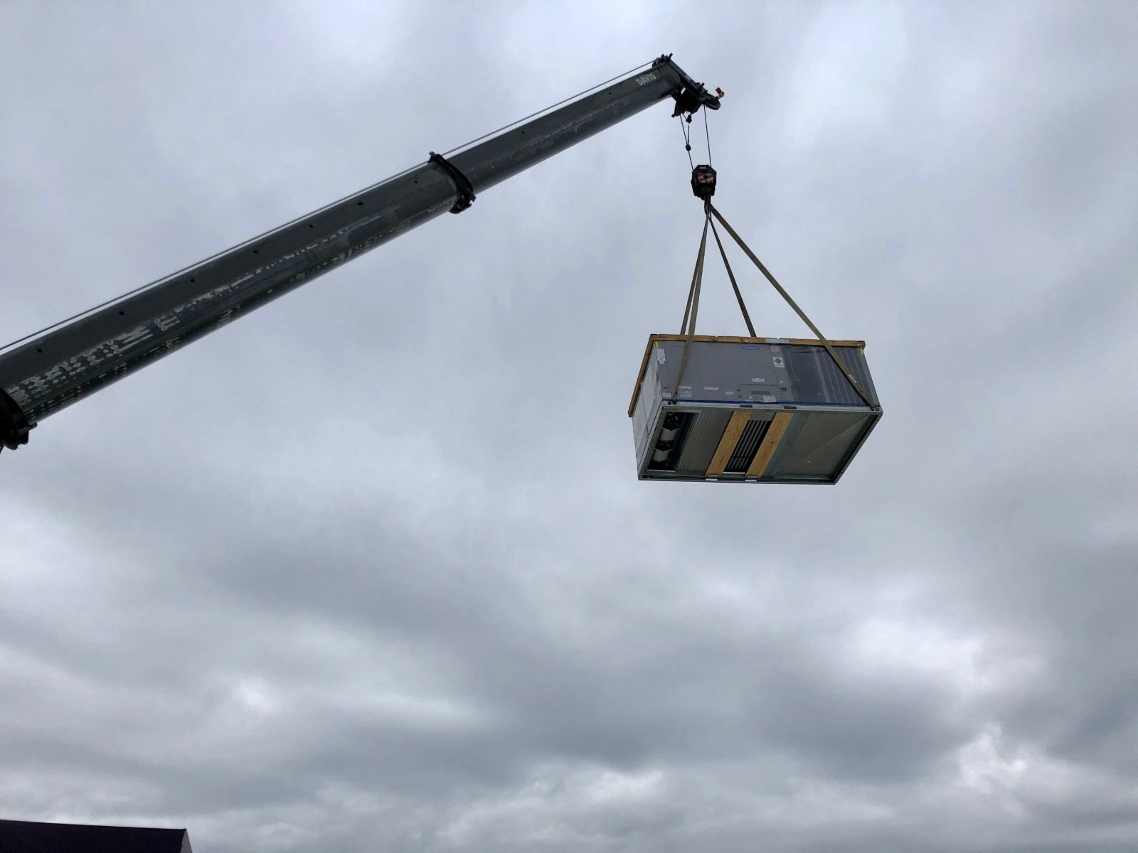 Carrier packaged rooftop unit rigged and lifted by crane at a self-storage facility