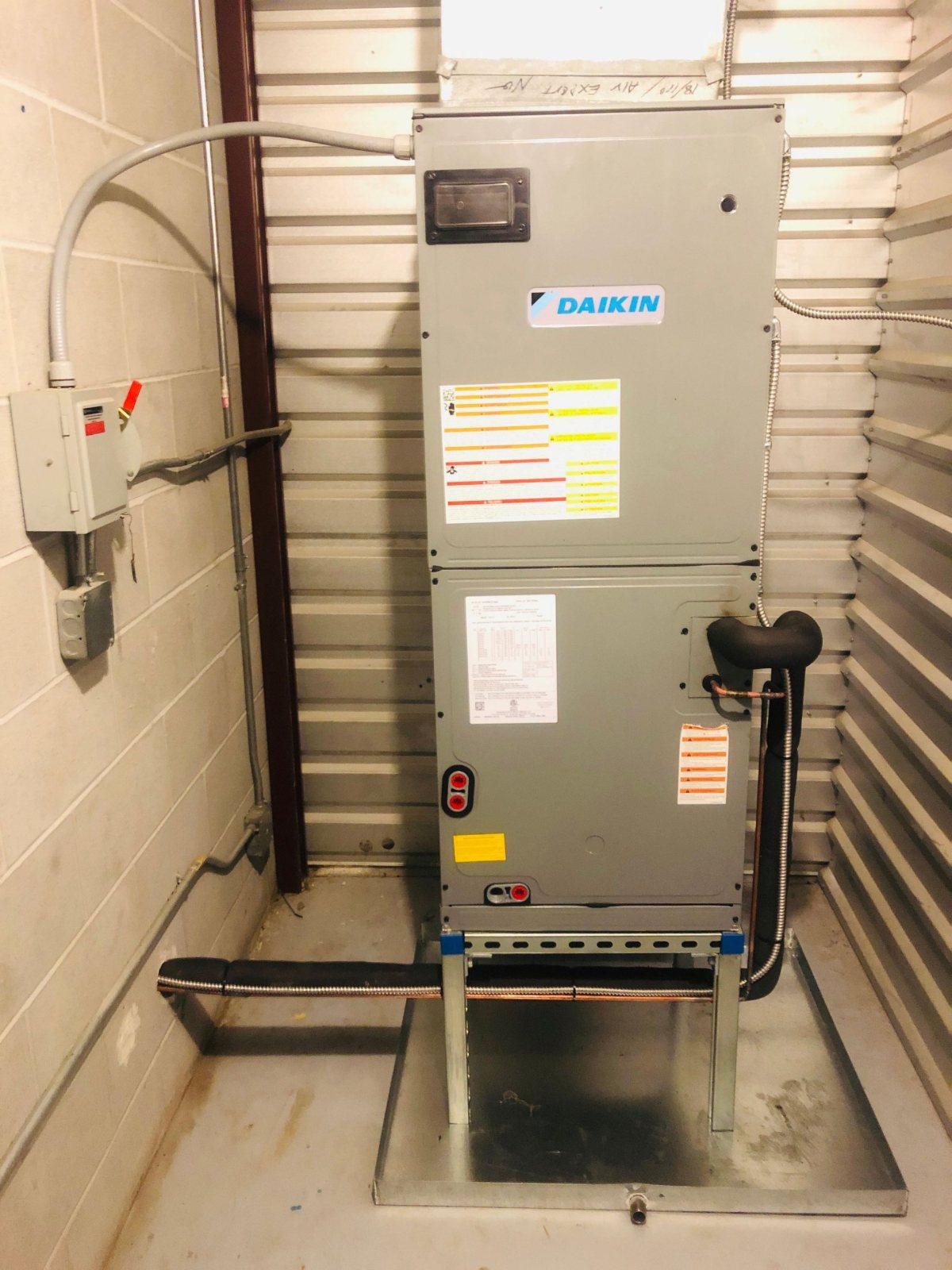 Daikin air handler raised on a Unistrut stand over a galvanized secondary drain pan, with disconnect and flex conduit, Houston