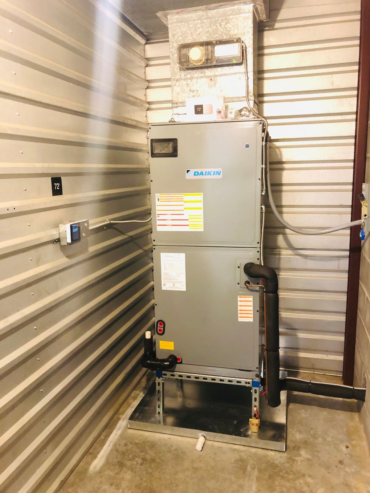 Daikin vertical air handler on a Unistrut stand with secondary drain pan, float switch, and duct smoke detector in a Houston self-storage mechanical closet