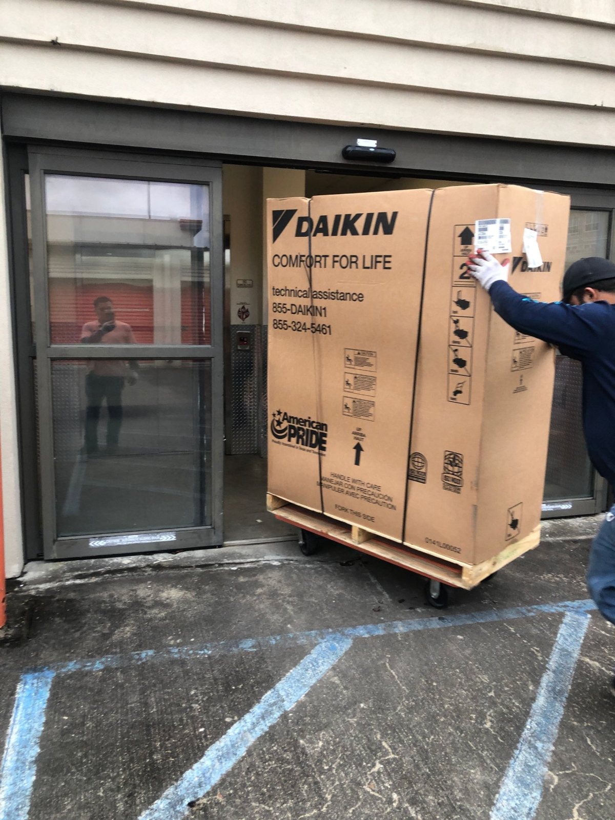 Comfort Mechanical crew bringing a palletized Daikin air handler into a Houston self-storage building