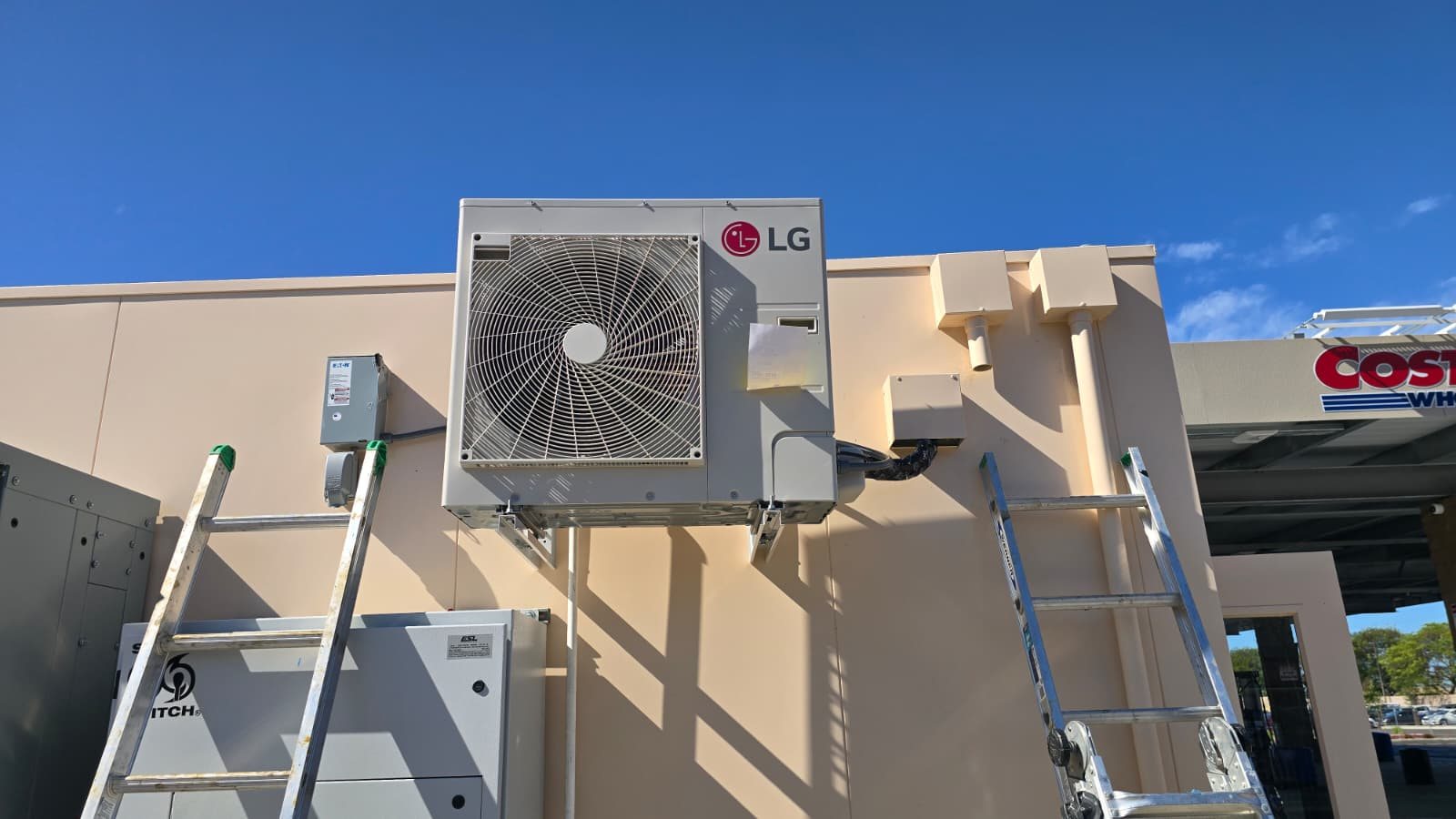 Install day at a new fuel station: LG condenser on wall brackets at the data hut, ladders in place