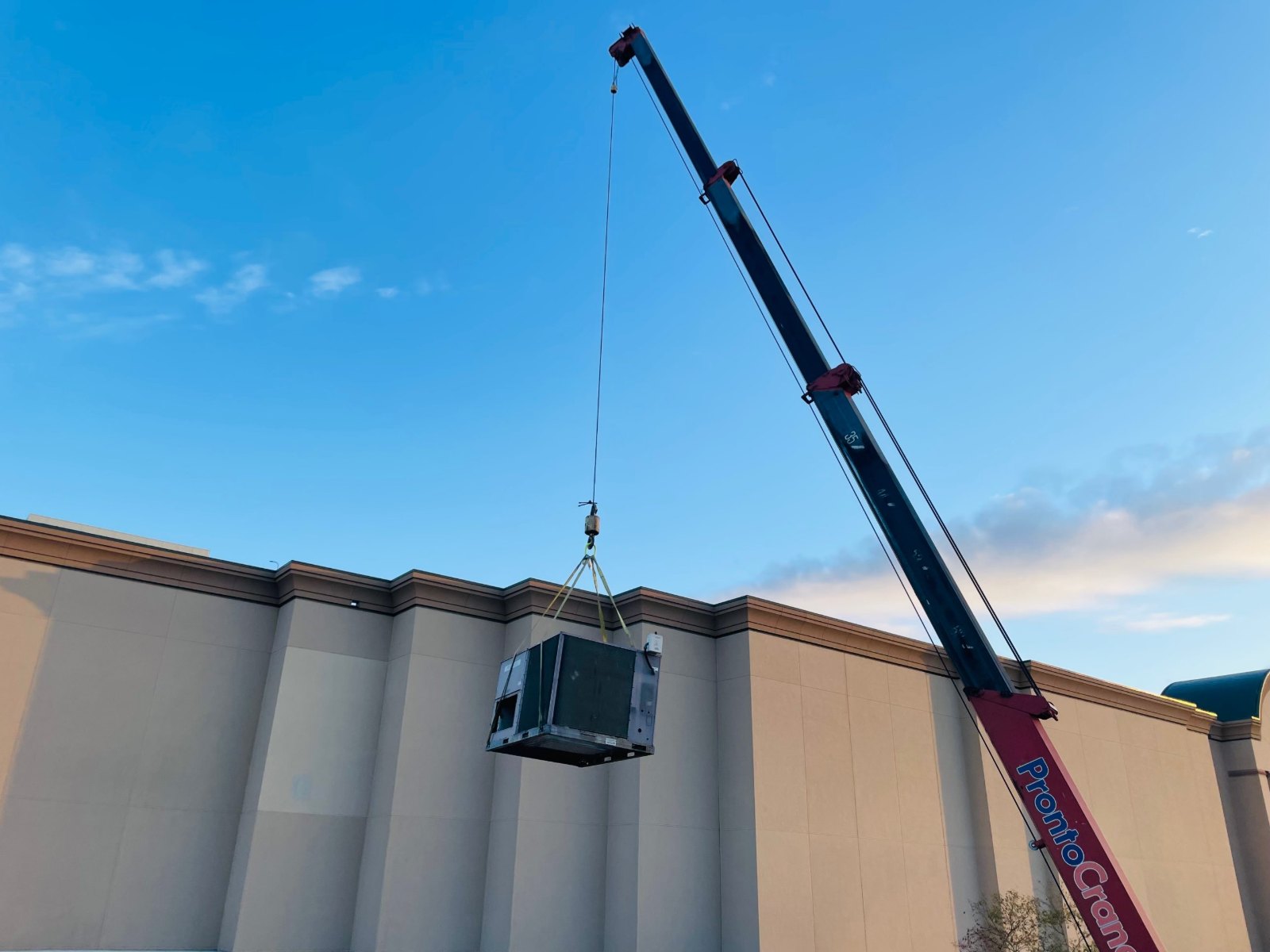 Rooftop HVAC unit lifted by crane at Willowbrook Mall in Houston for the Garage store mechanical buildout